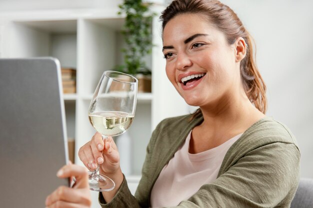 Frau, die Glas Wein trinkt, während Laptop verwendet