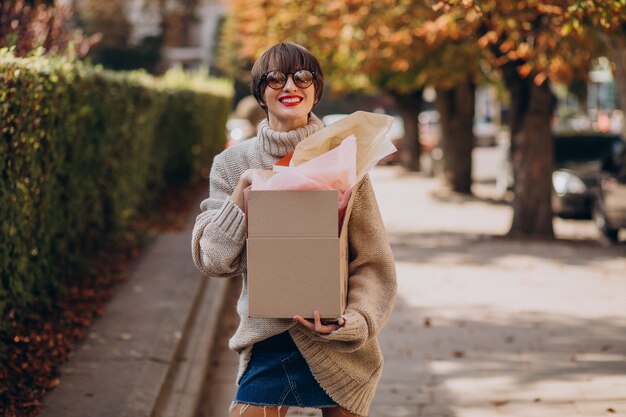 Frau, die große Paketbox hält und in der Straße geht