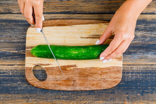 Frau, die Gurke mit Messer schneidet