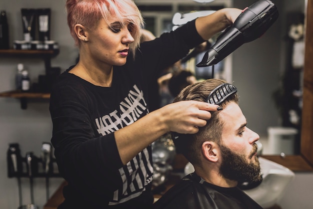 Kostenloses Foto frau, die haar des kunden kämmt und trocknet