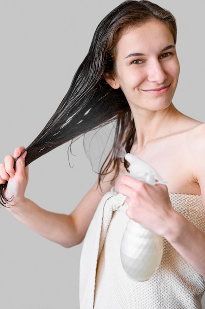 Frau, die Haar mit Produkt besprüht