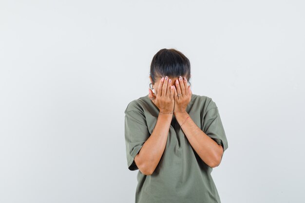 Frau, die Hände auf Gesicht im T-Shirt hält und deprimiert aussieht