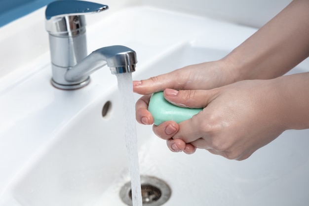 Frau, die Hände sorgfältig im Badezimmer nah oben wäscht. Prävention von Infektionen und der Ausbreitung von Grippeviren