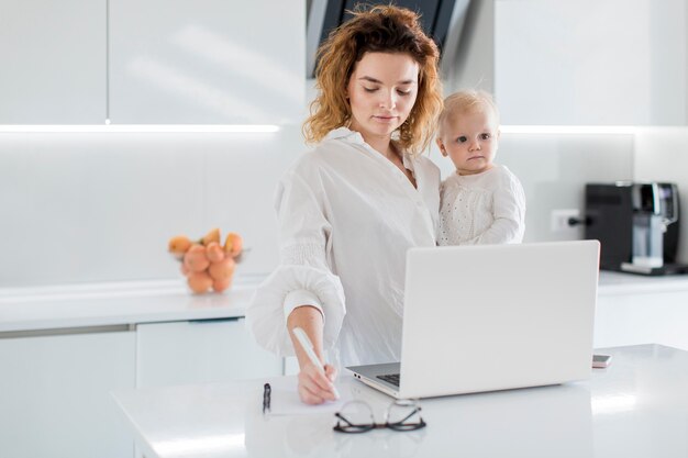 Frau, die haltendes Baby schreibt