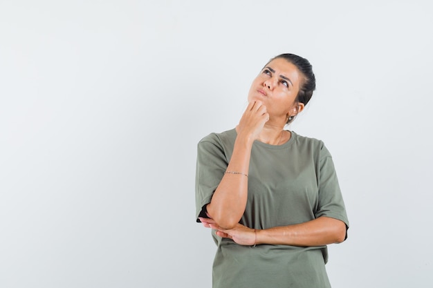 Frau, die Hand am Kinn im T-Shirt hält und nachdenklich schaut