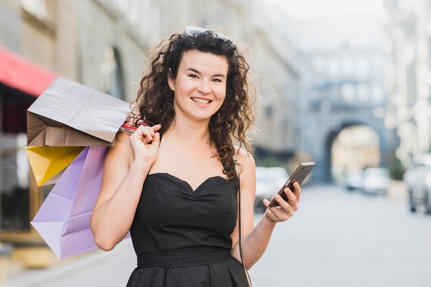 Frau, die Handy beim Einkauf auf Straße verwendet