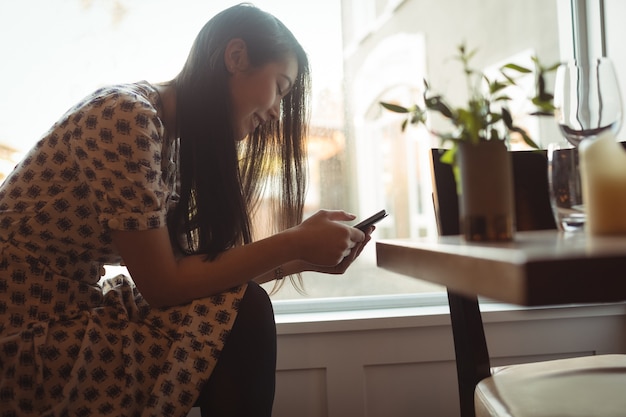 Kostenloses Foto frau, die handy nahe fenster verwendet