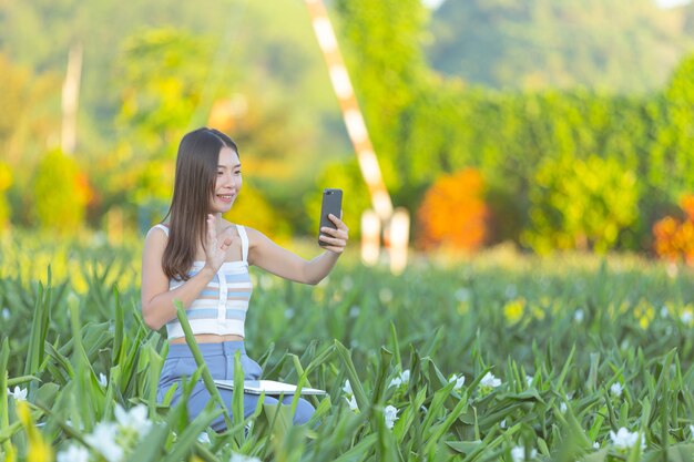 Frau, die Handy verwendet, um Foto im Blumengarten zu machen.