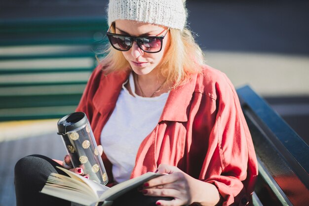 Frau, die heißes Getränk und Buch genießt