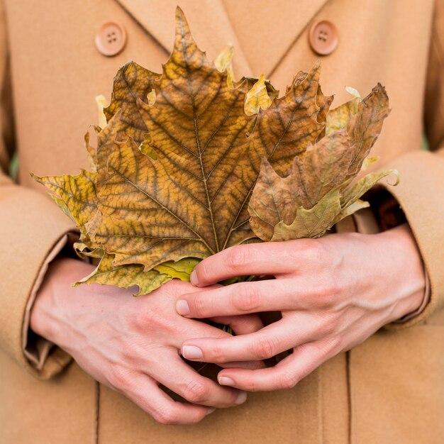 Frau, die Herbstblätter hält