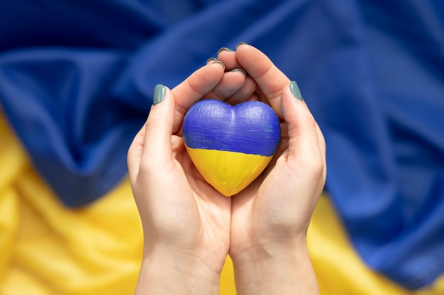 Kostenloses Foto frau, die herz mit ukrainischer flagge über einer anderen flagge hält