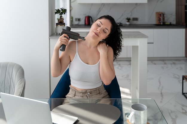 Kostenloses Foto frau, die hohen winkel der massagepistole verwendet