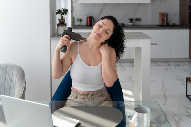 Frau, die hohen Winkel der Massagepistole verwendet