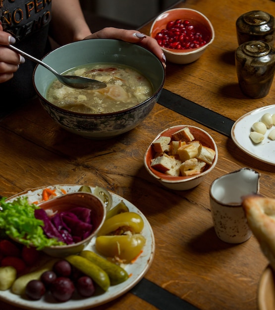 Frau, die Hühnersuppe mit Kräutern und Gewürzen herum isst