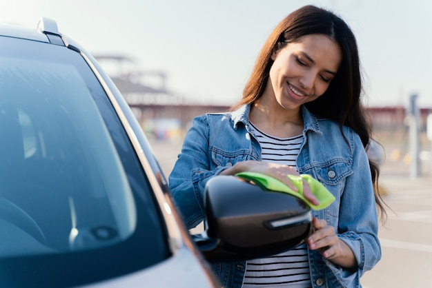 Kostenloses Foto frau, die ihr auto draußen putzt