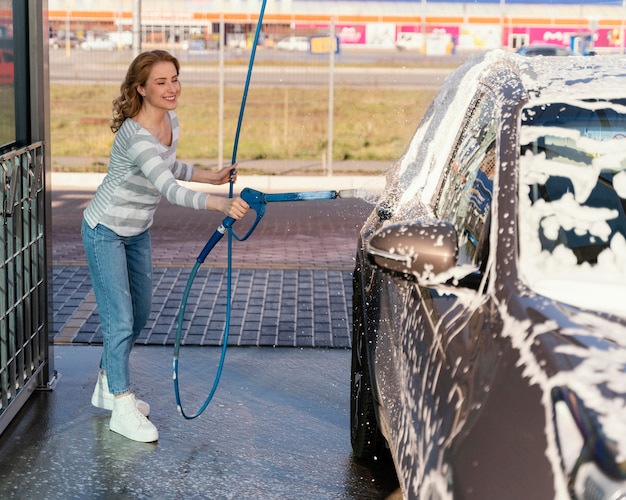 Frau, die ihr Auto draußen wäscht