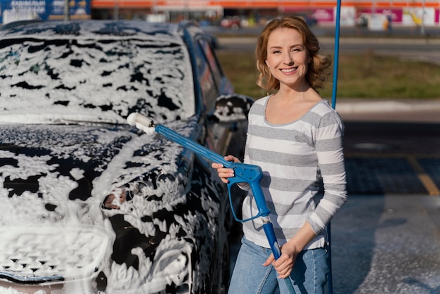 Frau, die ihr Auto draußen wäscht