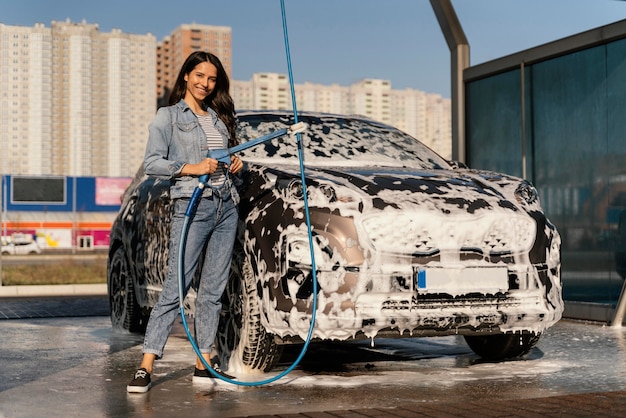 Kostenloses Foto frau, die ihr auto draußen wäscht