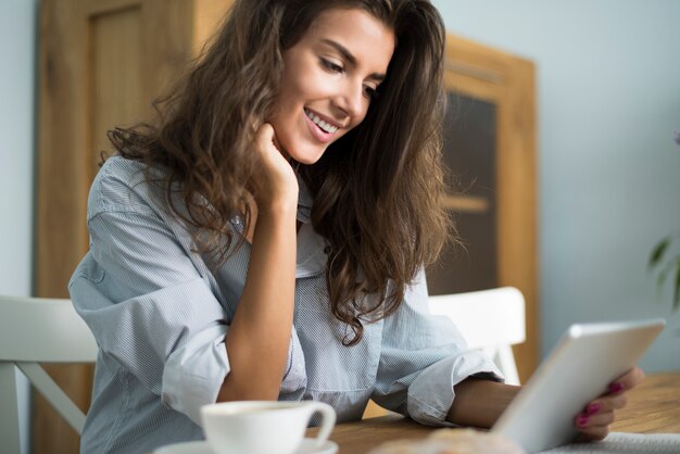 Frau, die ihr digitales Tablett am Morgen durchsucht