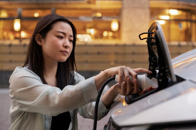 Frau, die ihr Elektroauto an der Station auflädt