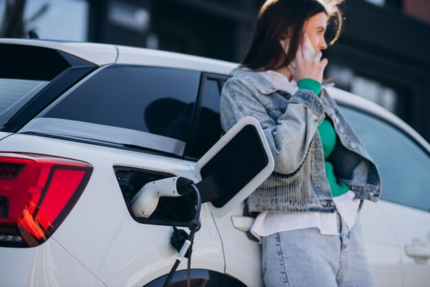 Frau, die ihr Elektroauto mit Ladepistole auflädt