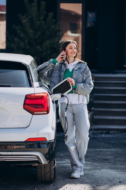 Frau, die ihr Elektroauto mit Ladepistole auflädt