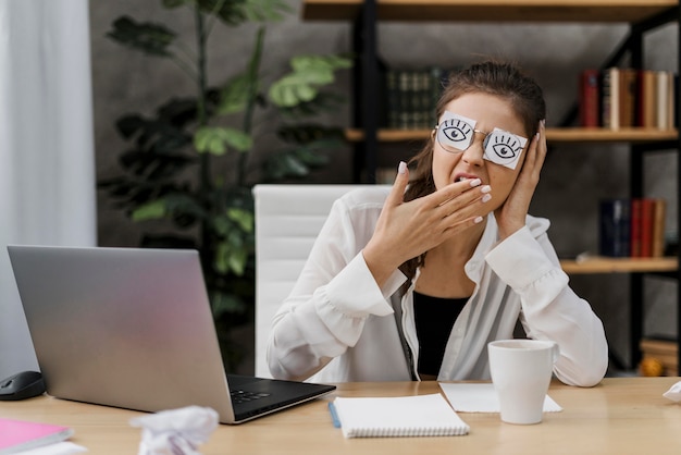 Frau, die ihre Augen mit gezeichneten Augen auf Papier bedeckt