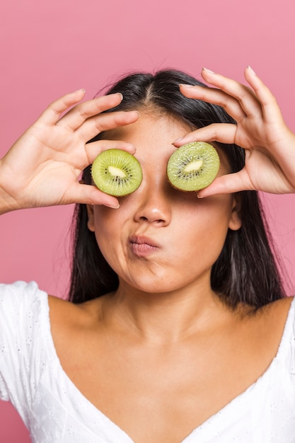 Frau, die ihre augen mit kiwi sich wundert und bedeckt