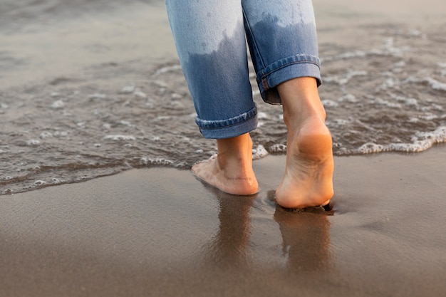 Frau, die ihre Füße im Wasser am Strand bekommt