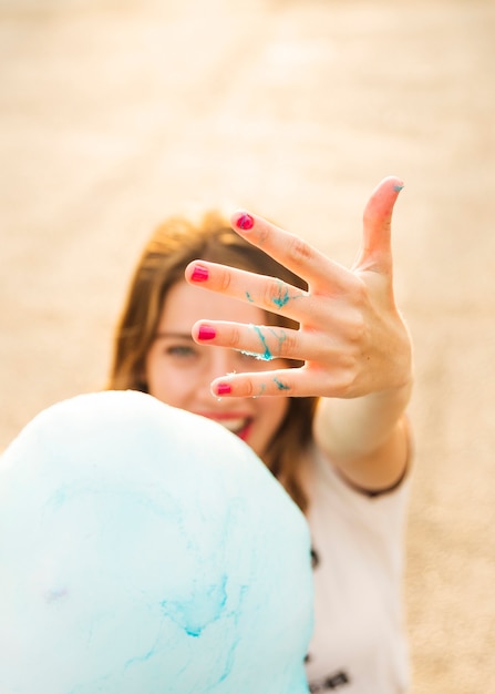 Frau, die ihre Hand mit blauer Zuckerwatte zeigt