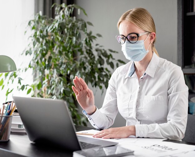 Frau, die ihre Klassen tut, während sie eine Gesichtsmaske trägt