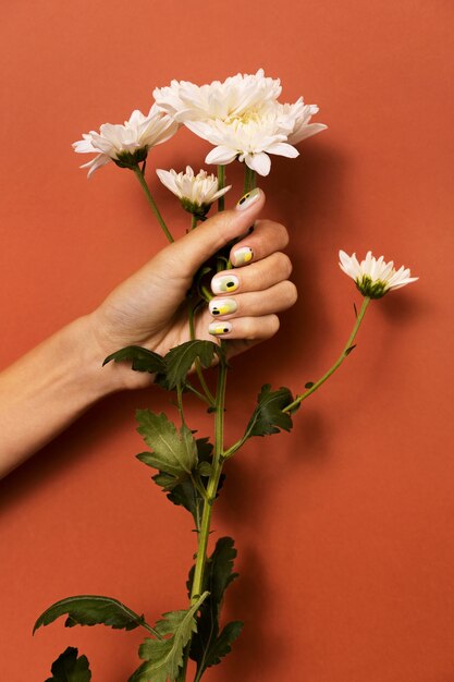 Frau, die ihre Nagelkunst auf Fingernägeln mit Blume zeigt