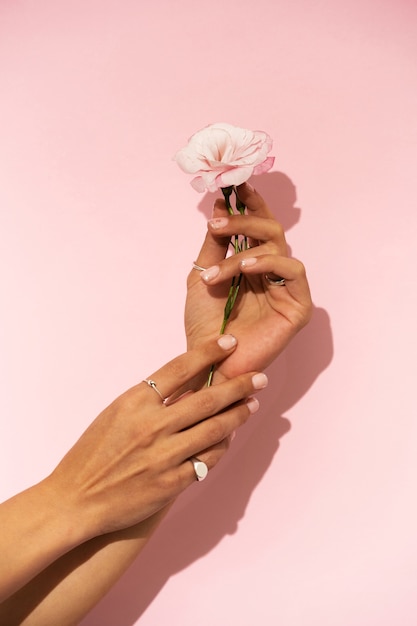 Frau, die ihre Nagelkunst auf Fingernägeln mit Blume zeigt