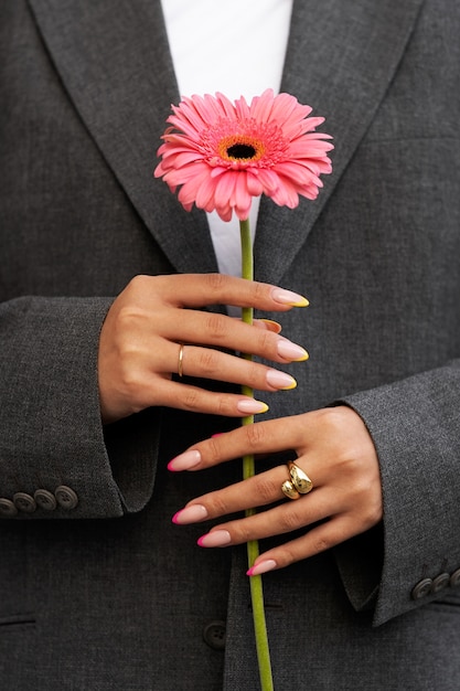 Frau, die ihre Nagelkunst auf Fingernägeln mit Blume zeigt