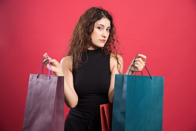 Frau, die ihre neuen Kaufkleidung auf rotem Hintergrund zeigt. Hochwertiges Foto