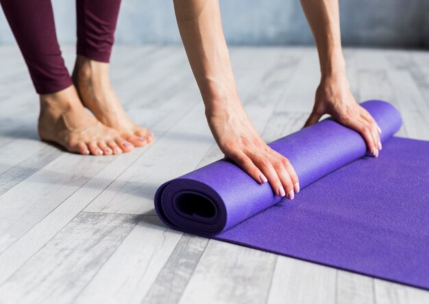 Frau, die ihre Yogamatte rollt