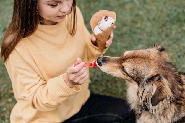 Frau, die ihrem Hund Eis gibt