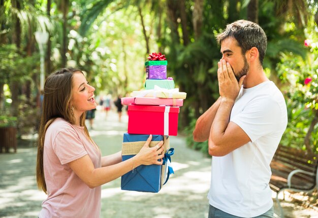 Frau, die ihrem überraschten Freund Stapel Geschenke gibt