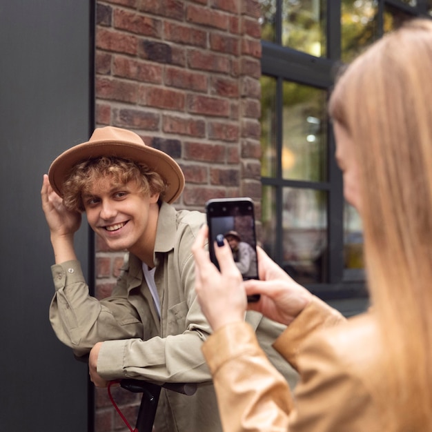 Kostenloses Foto frau, die ihren freund mit elektroroller fotografiert