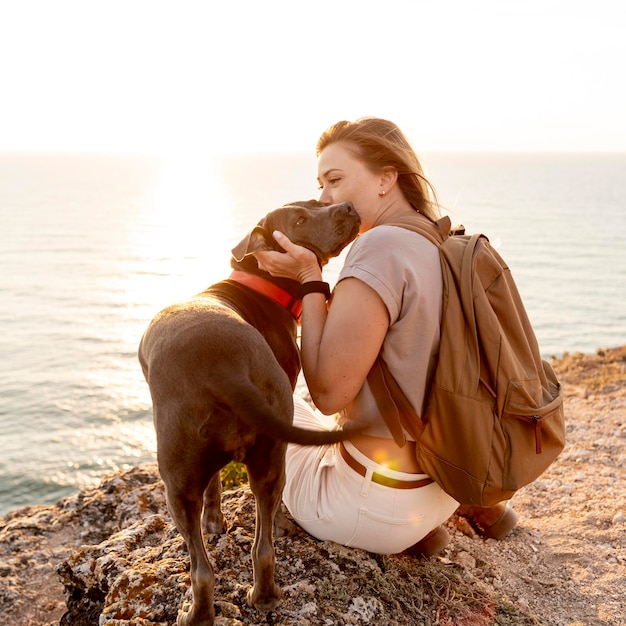 Frau, die ihren Hund bei Sonnenuntergang umarmt