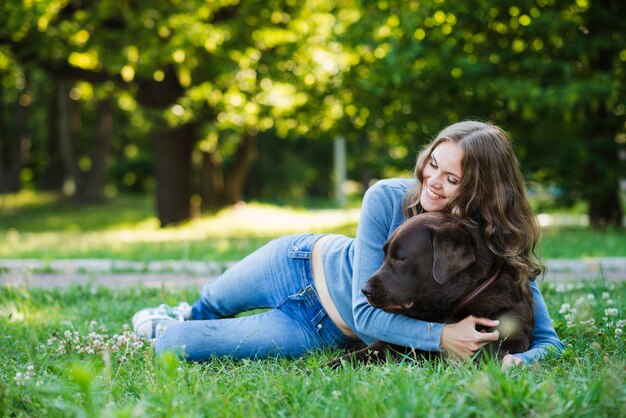 Frau, die ihren Hund im Park umarmt