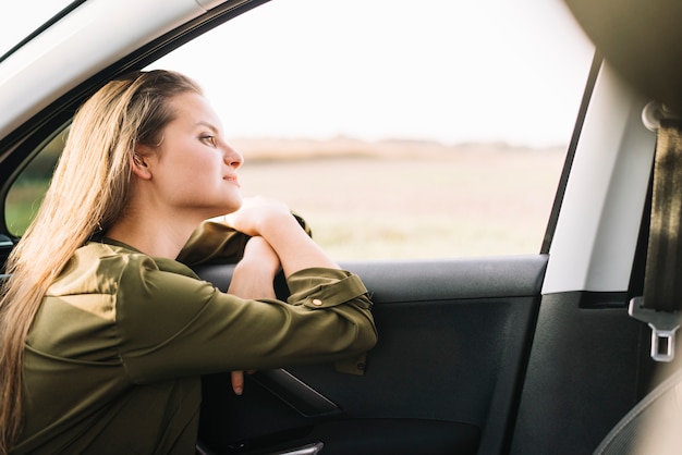 Kostenloses Foto frau, die im auto sitzt und weg schaut