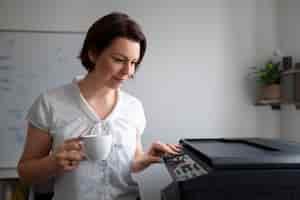 Kostenloses Foto frau, die im büro arbeitet und drucker verwendet