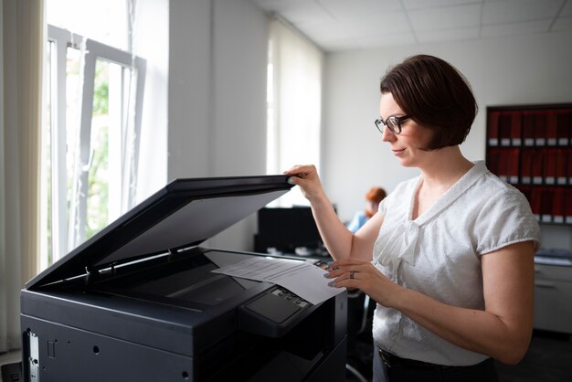 Frau, die im Büro arbeitet und Drucker verwendet