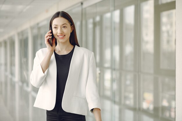 Frau, die im Büro mit einem Telefon steht