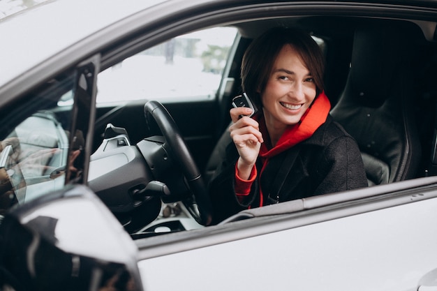 Frau, die im Elektroauto sitzt, während es auflädt