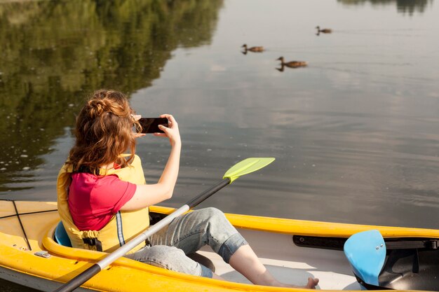 Frau, die im Kajak bleibt und Fotos macht