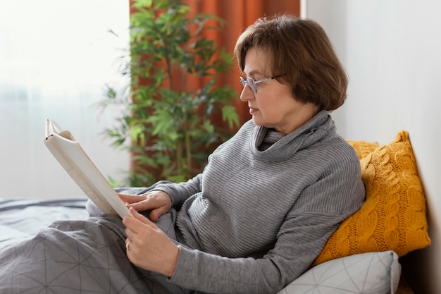 Kostenloses Foto frau, die im mittleren medium des bettes liest