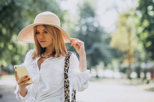 Frau, die im Park geht und am Telefon spricht