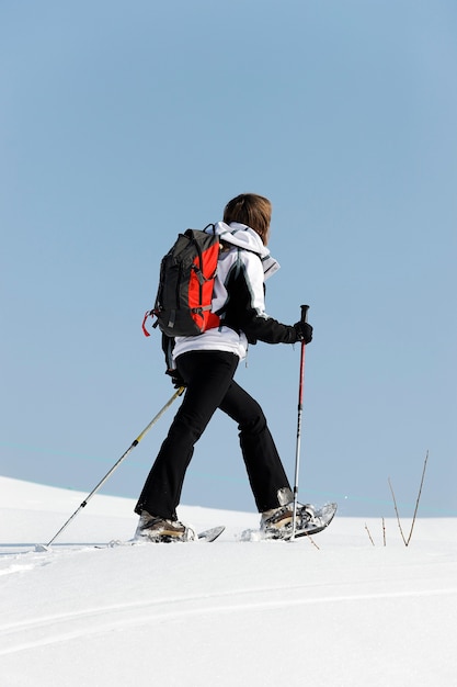 Frau, die im Schnee mit Schlägern geht